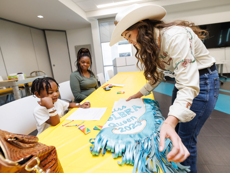 Children's of Mississippi patient Antwon Coleman of Hermanville gets to see the chaps of Mid-South Little Britches Rodeo Association Queen Josi Johnson as mom Diane Davis looks on.